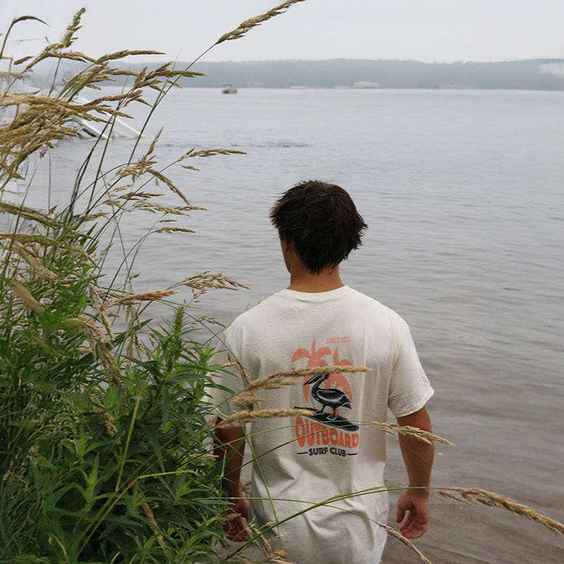 Person standing by a lake with tall grass in the foreground