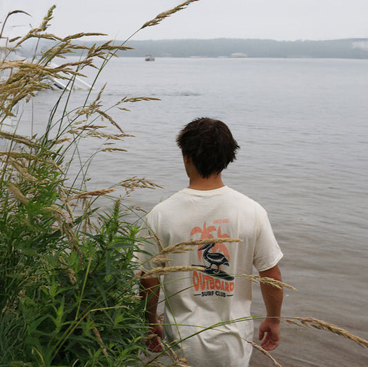 Person standing by a lake with tall grass in the foreground
